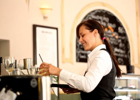 joven camarera contenta sirve zumos tras la barra
